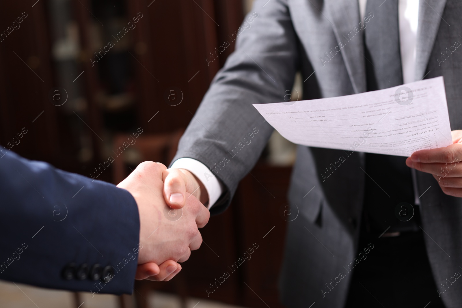 Photo of Notary shaking hands with client in office, closeup