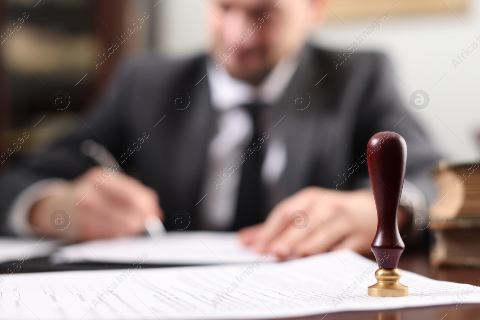 Photo of Notary working at table in office, focus on stamp