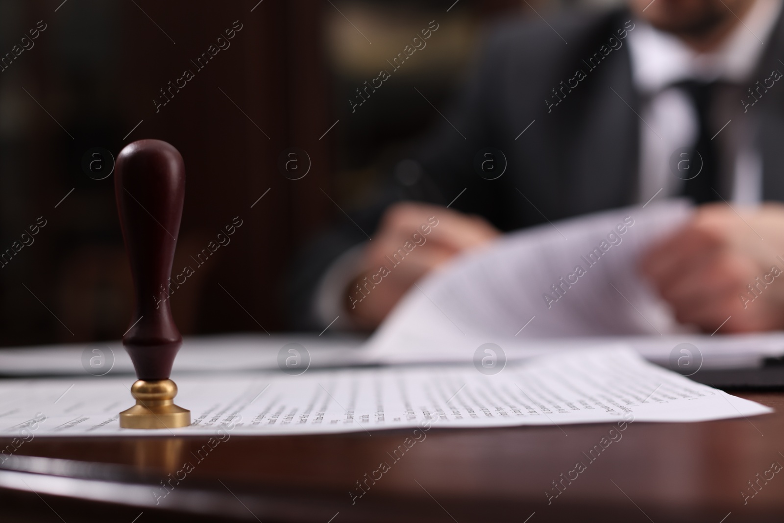 Photo of Notary working at table in office, focus on stamp