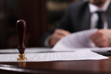 Photo of Notary working at table in office, focus on stamp