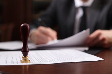 Photo of Notary working at table in office, focus on stamp