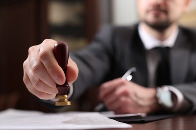 Photo of Notary stamping document at table in office, selective focus