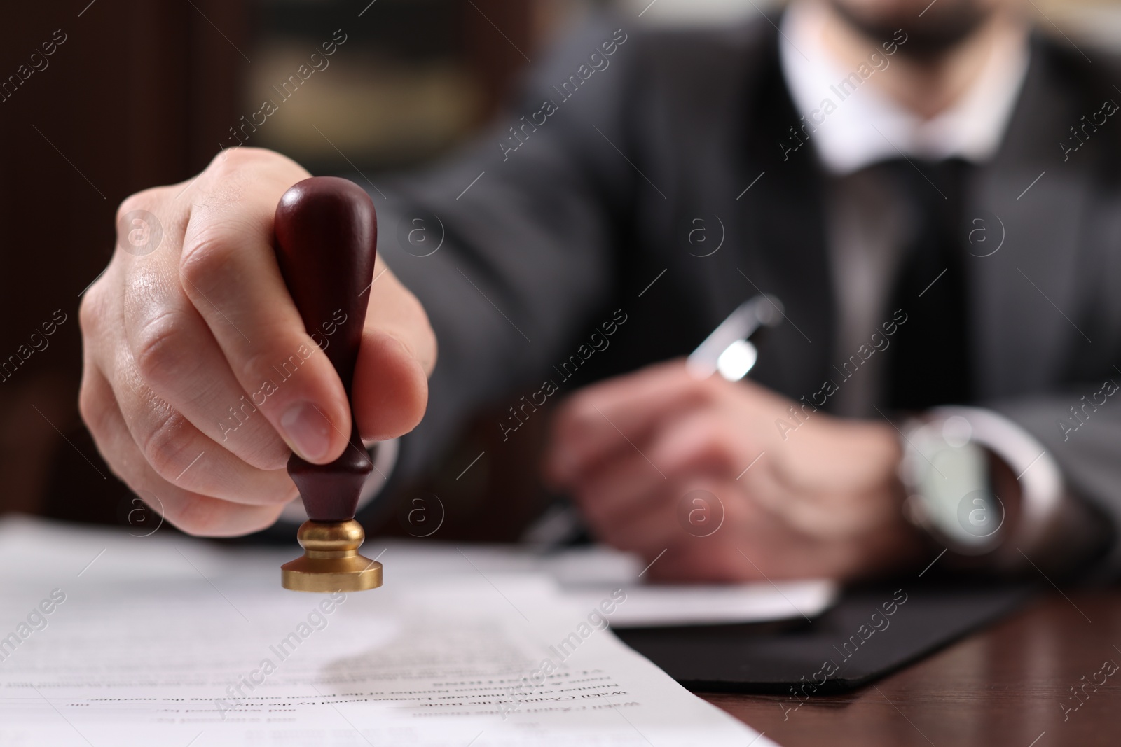 Photo of Notary stamping document at table in office, selective focus