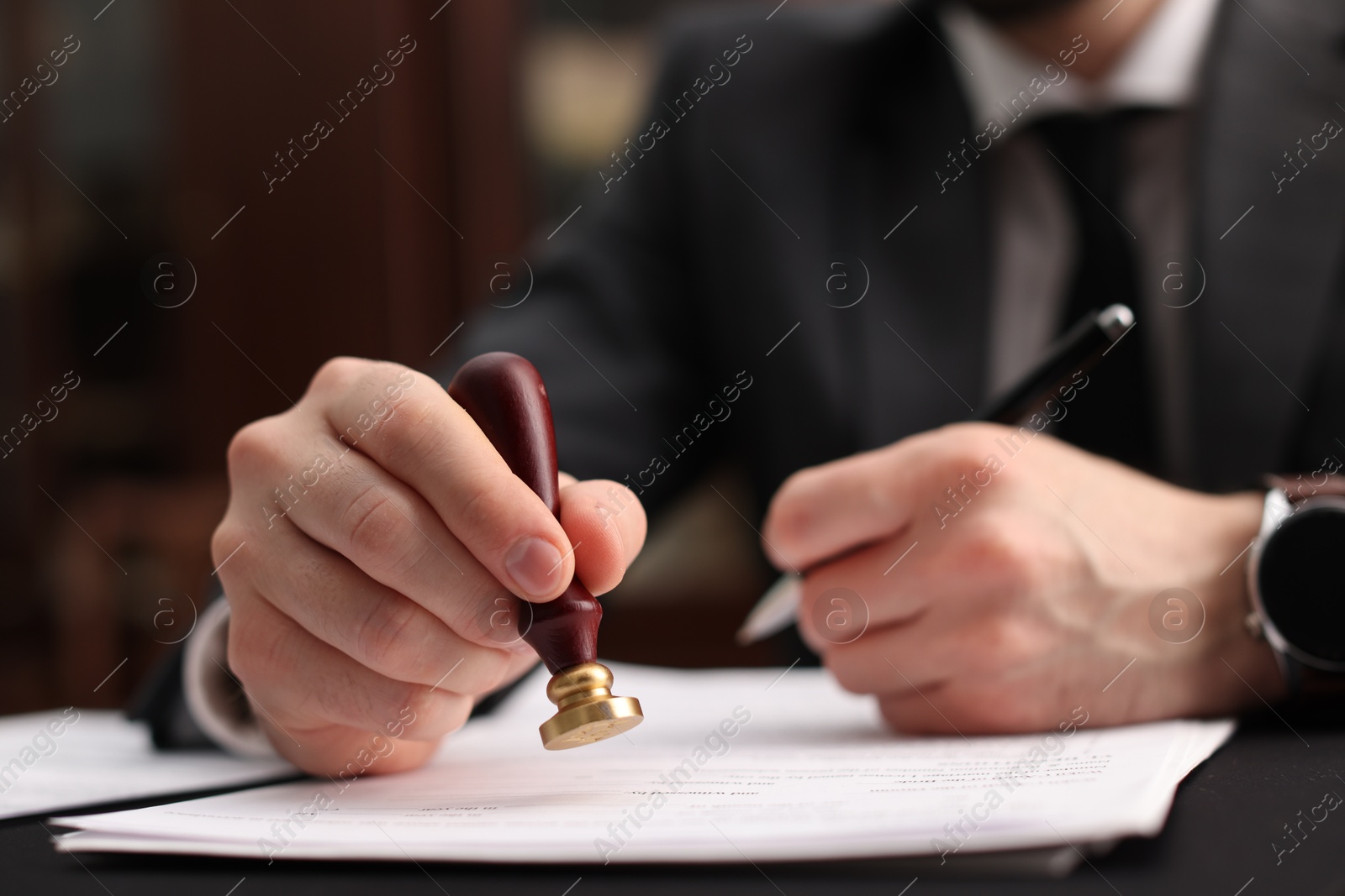 Photo of Notary stamping document at table in office, selective focus