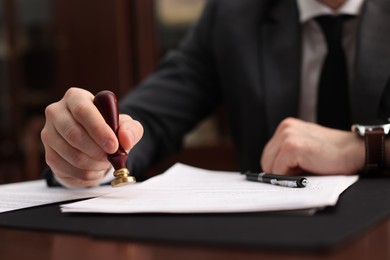 Photo of Notary stamping document at table in office, selective focus