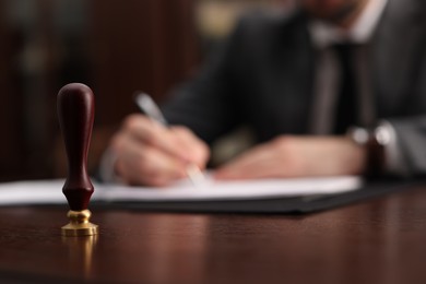 Photo of Notary working at table in office, focus on stamp