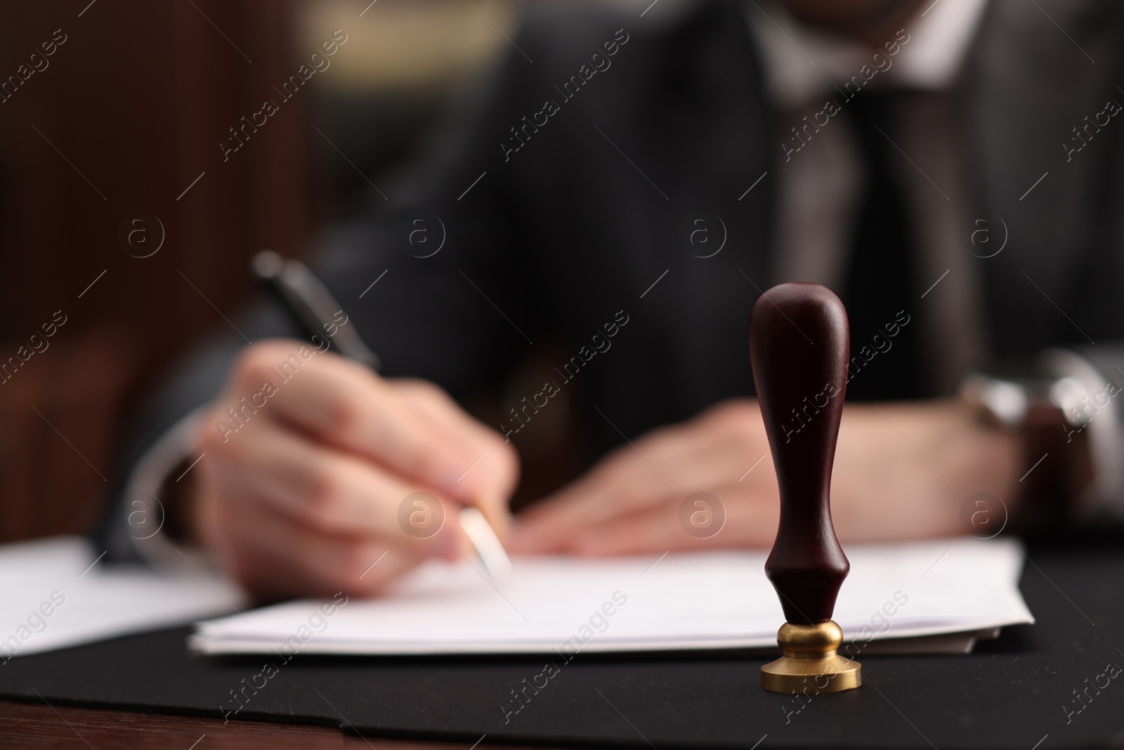 Photo of Notary working at table in office, focus on stamp