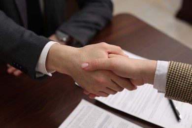 Photo of Notary shaking hands with client in office, closeup