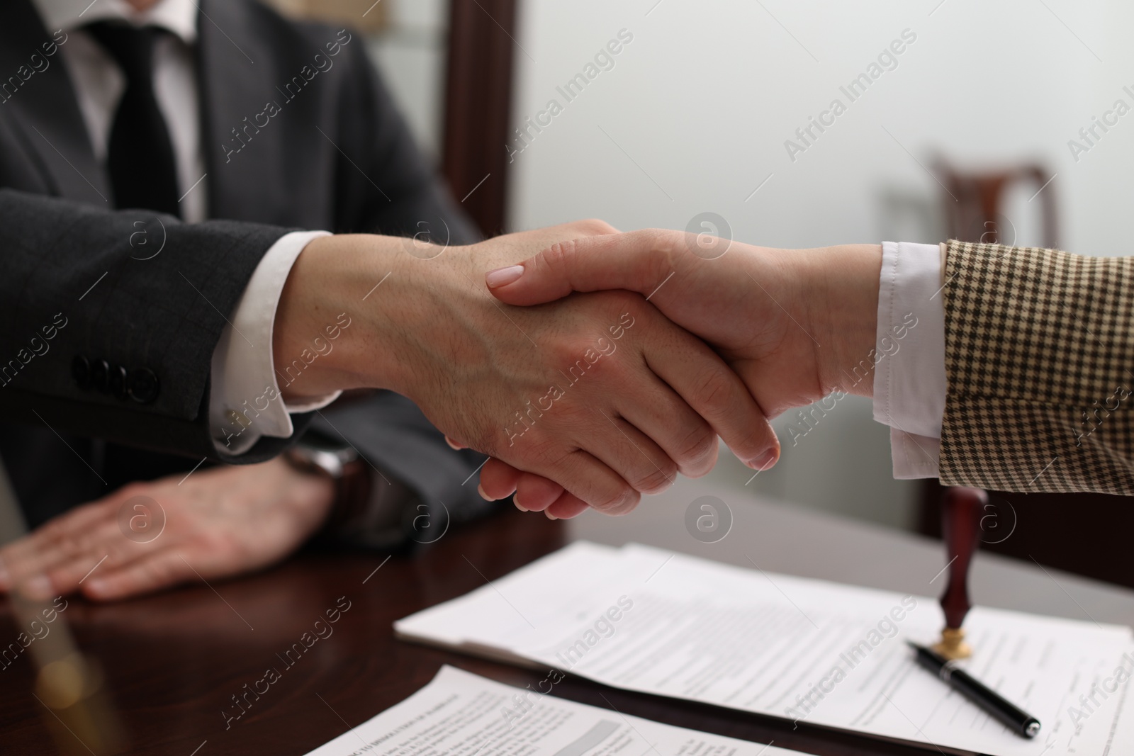 Photo of Notary shaking hands with client in office, closeup