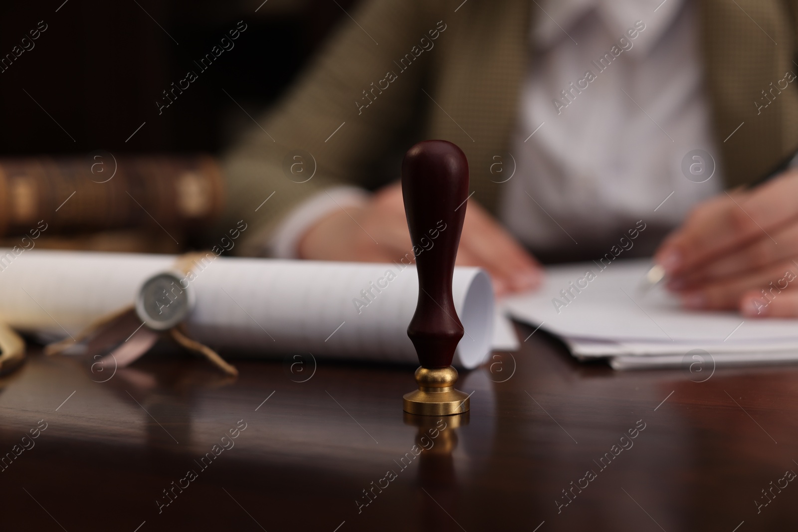 Photo of Notary working at table in office, focus on stamp