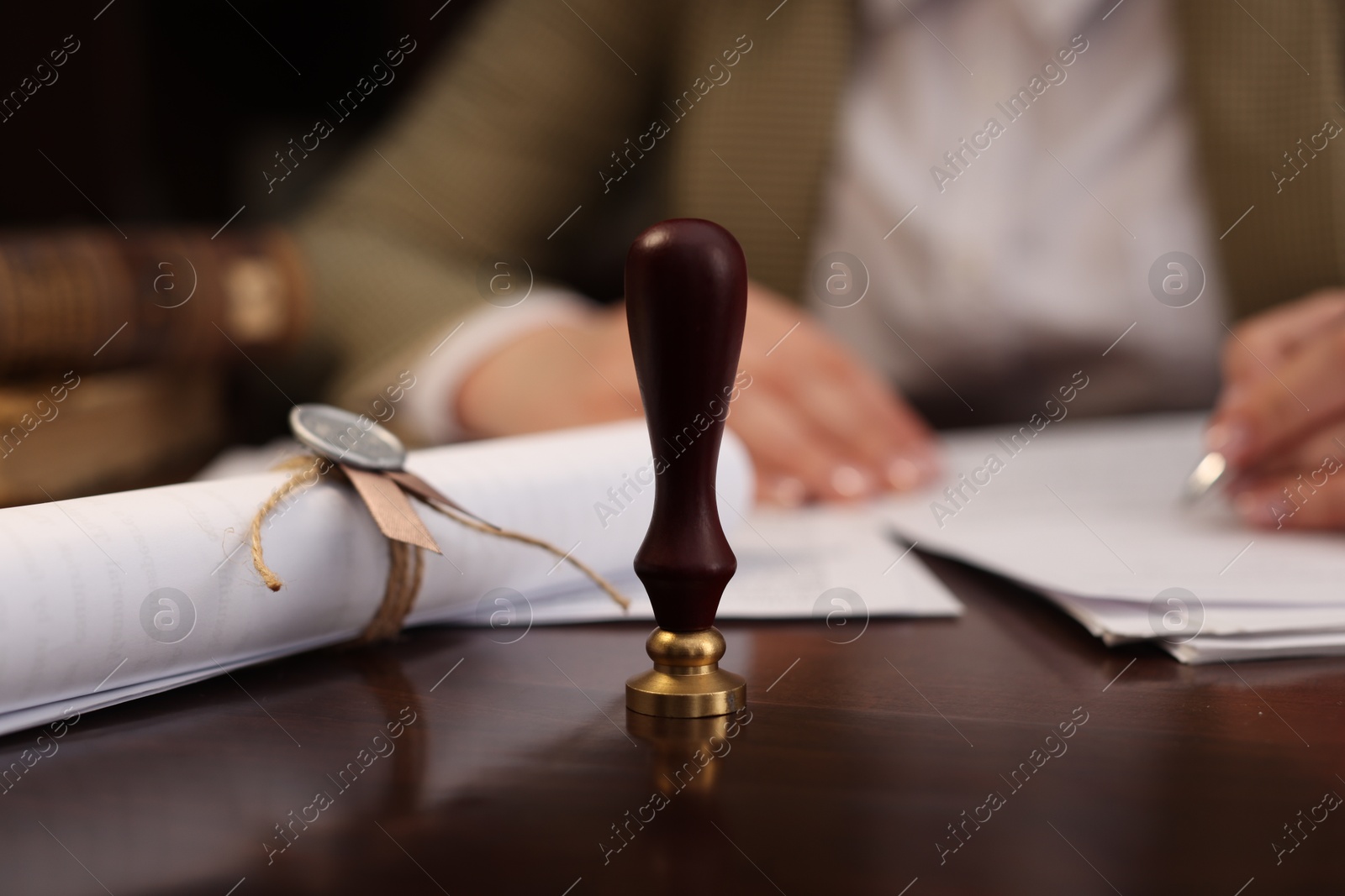 Photo of Notary working at table in office, focus on stamp