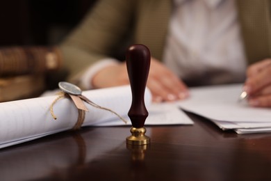 Photo of Notary working at table in office, focus on stamp