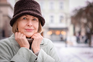 Photo of Portrait of beautiful senior woman on city street. Space for text