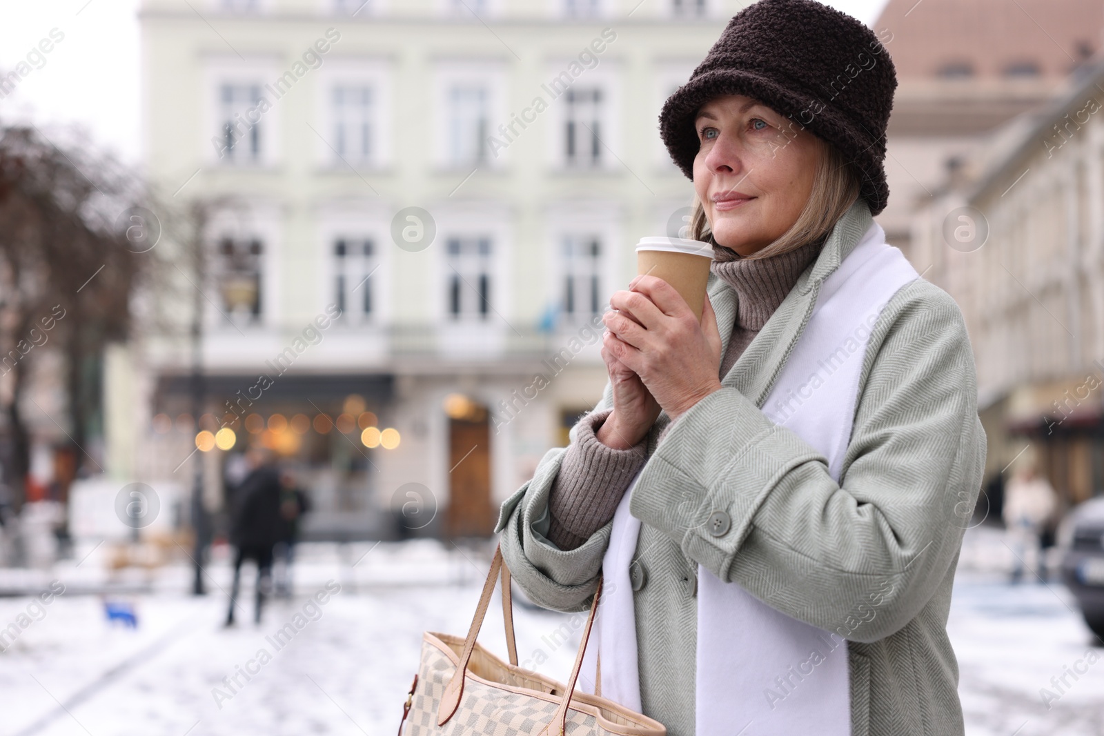 Photo of Beautiful senior woman with paper cup on city street. Space for text