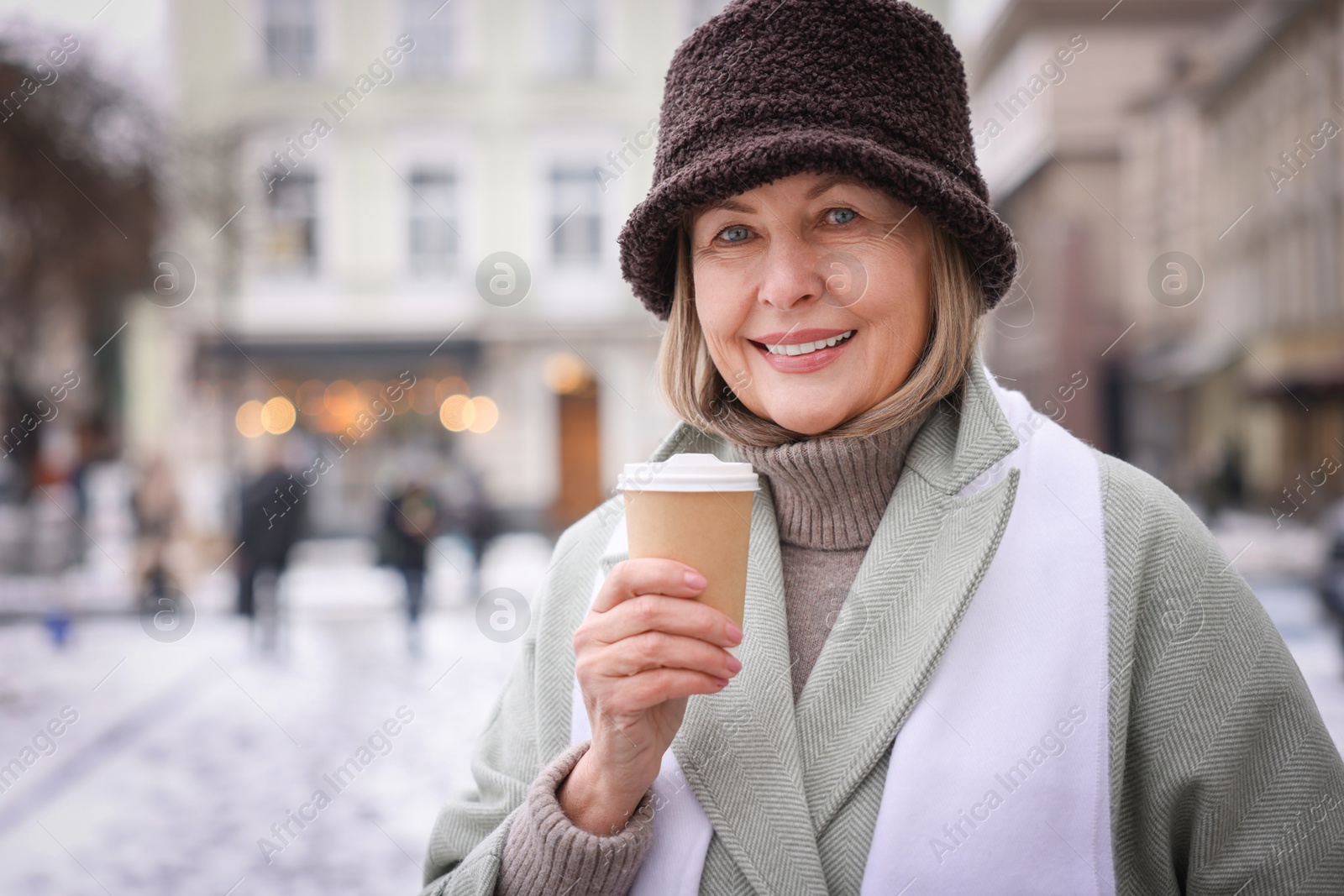 Photo of Smiling senior woman with paper cup on city street. Space for text