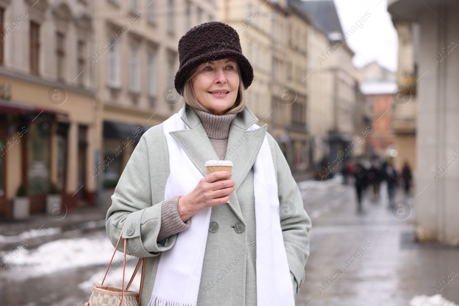 Photo of Smiling senior woman with paper cup on city street