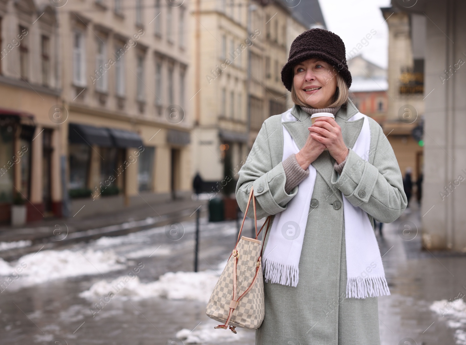 Photo of Smiling senior woman with paper cup on city street. Space for text