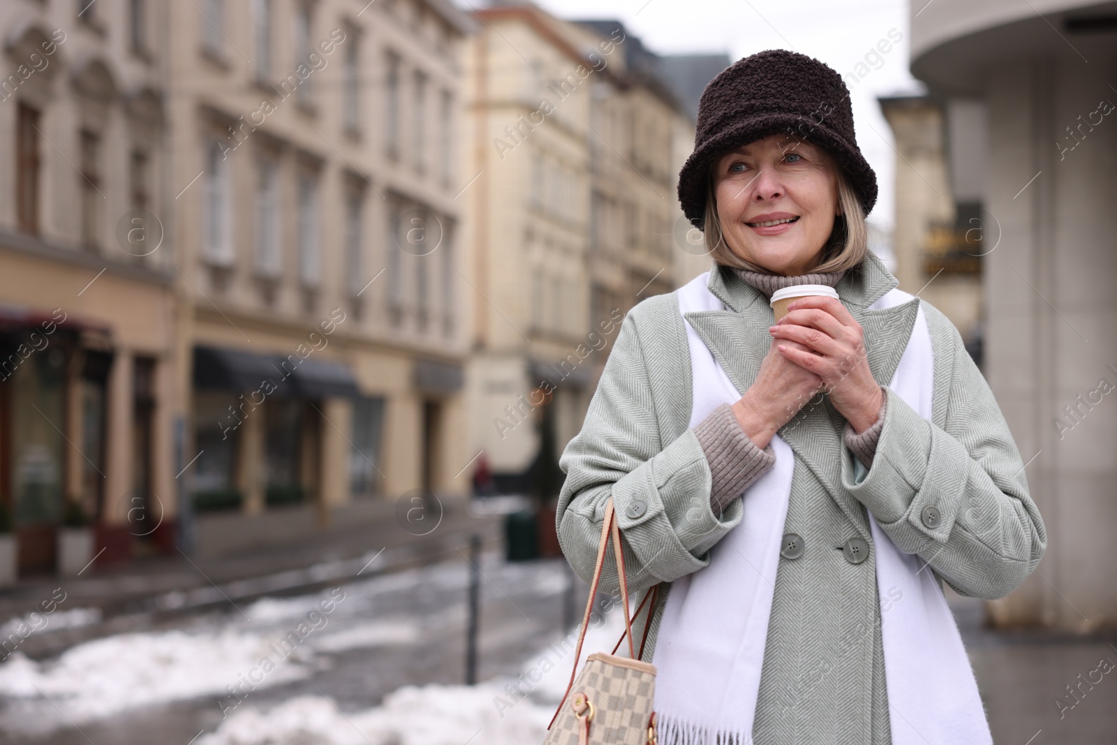 Photo of Smiling senior woman with paper cup on city street. Space for text