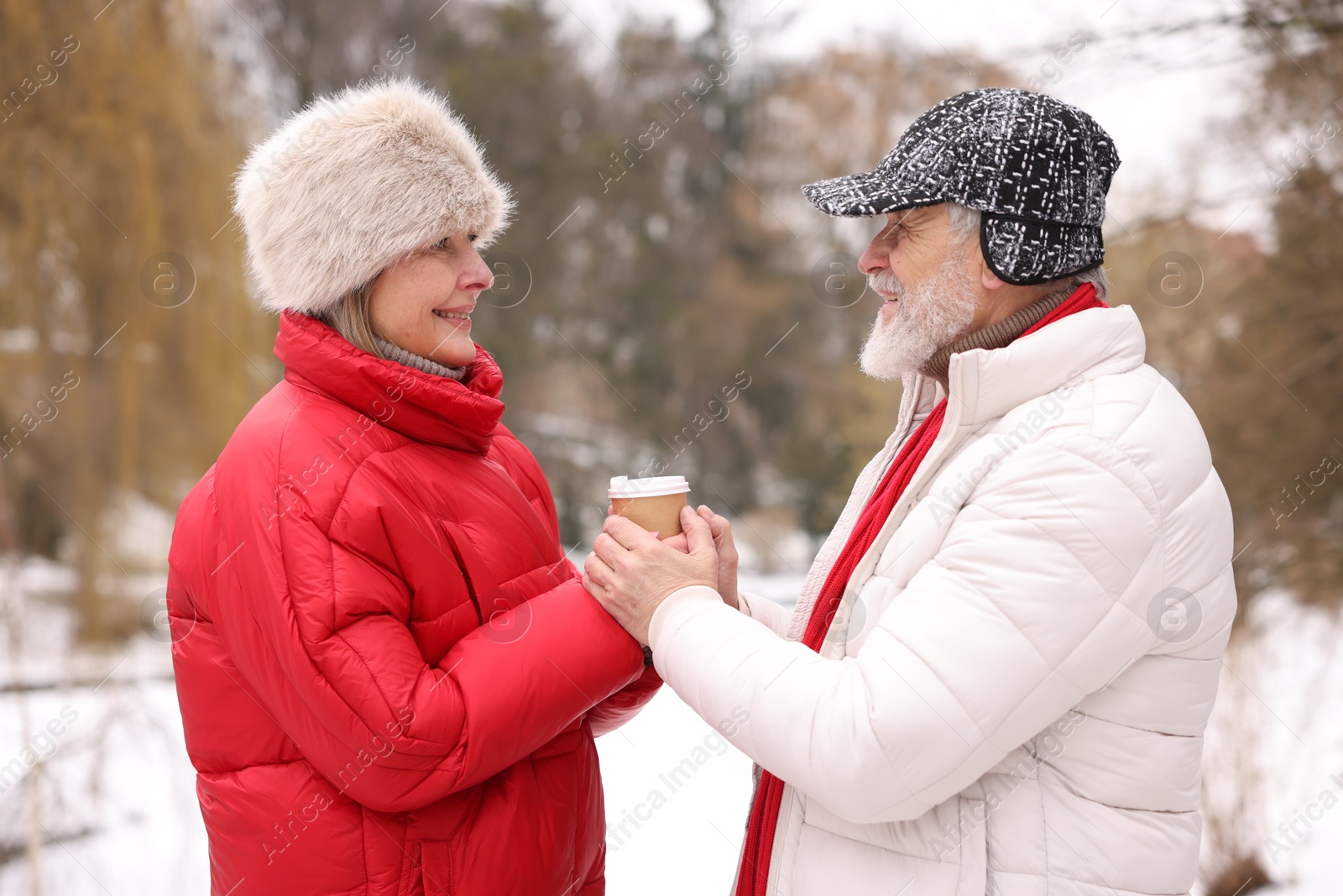 Photo of Happy senior couple with paper cup in winter park