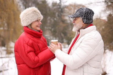 Photo of Happy senior couple with paper cup in winter park