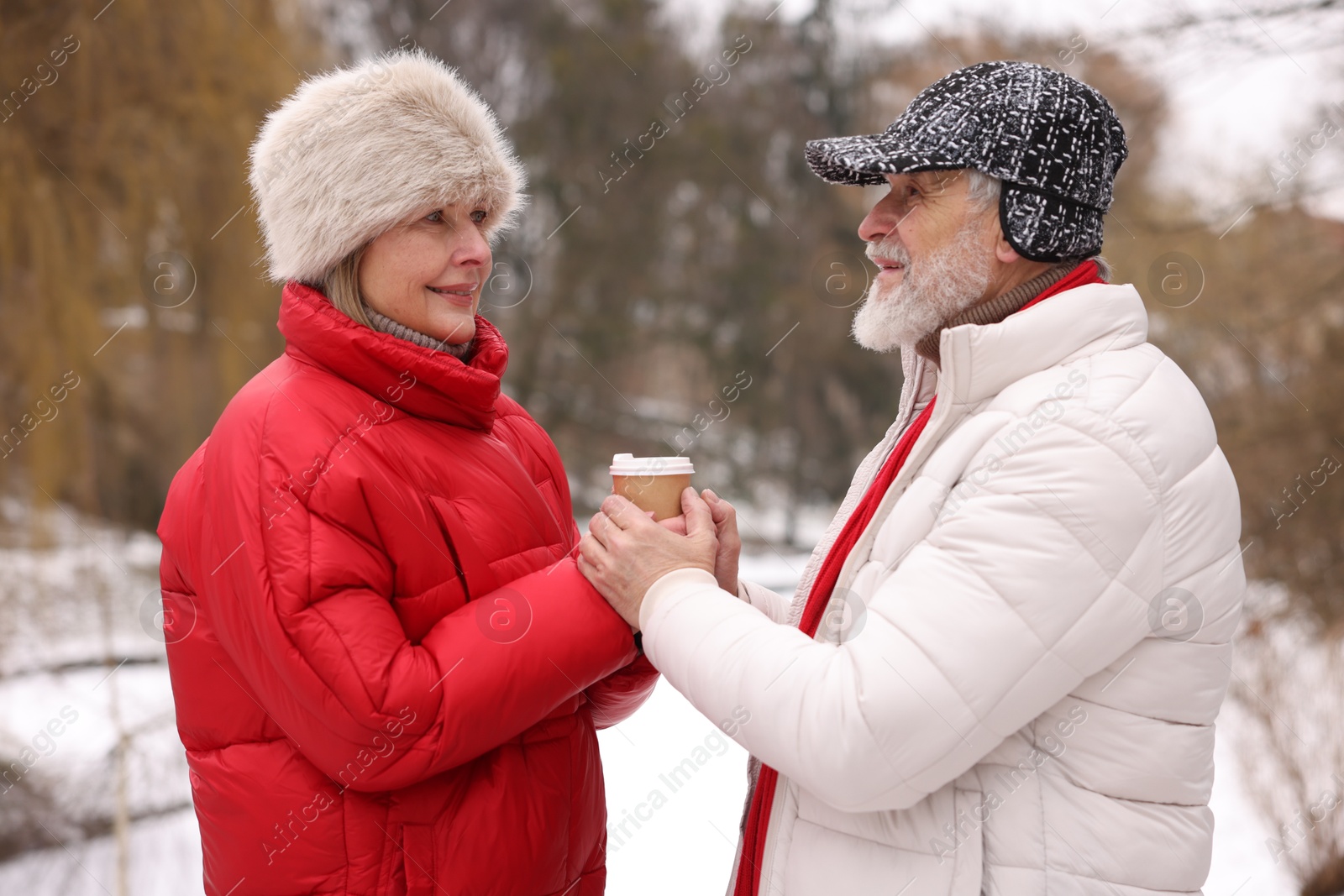 Photo of Happy senior couple with paper cup in winter park