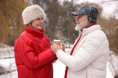 Photo of Happy senior couple with paper cup in winter park