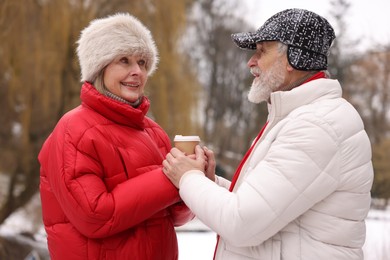 Photo of Happy senior couple with paper cup in winter park