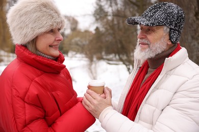 Photo of Happy senior couple with paper cup in winter park