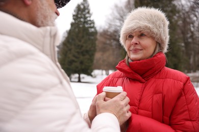 Photo of Lovely senior couple with paper cup in winter park