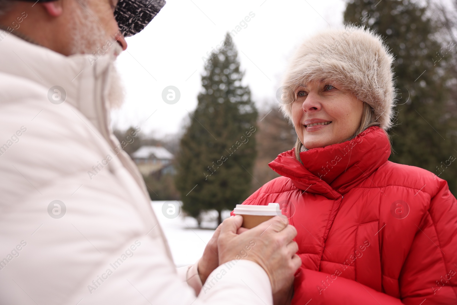 Photo of Lovely senior couple with paper cup in winter park