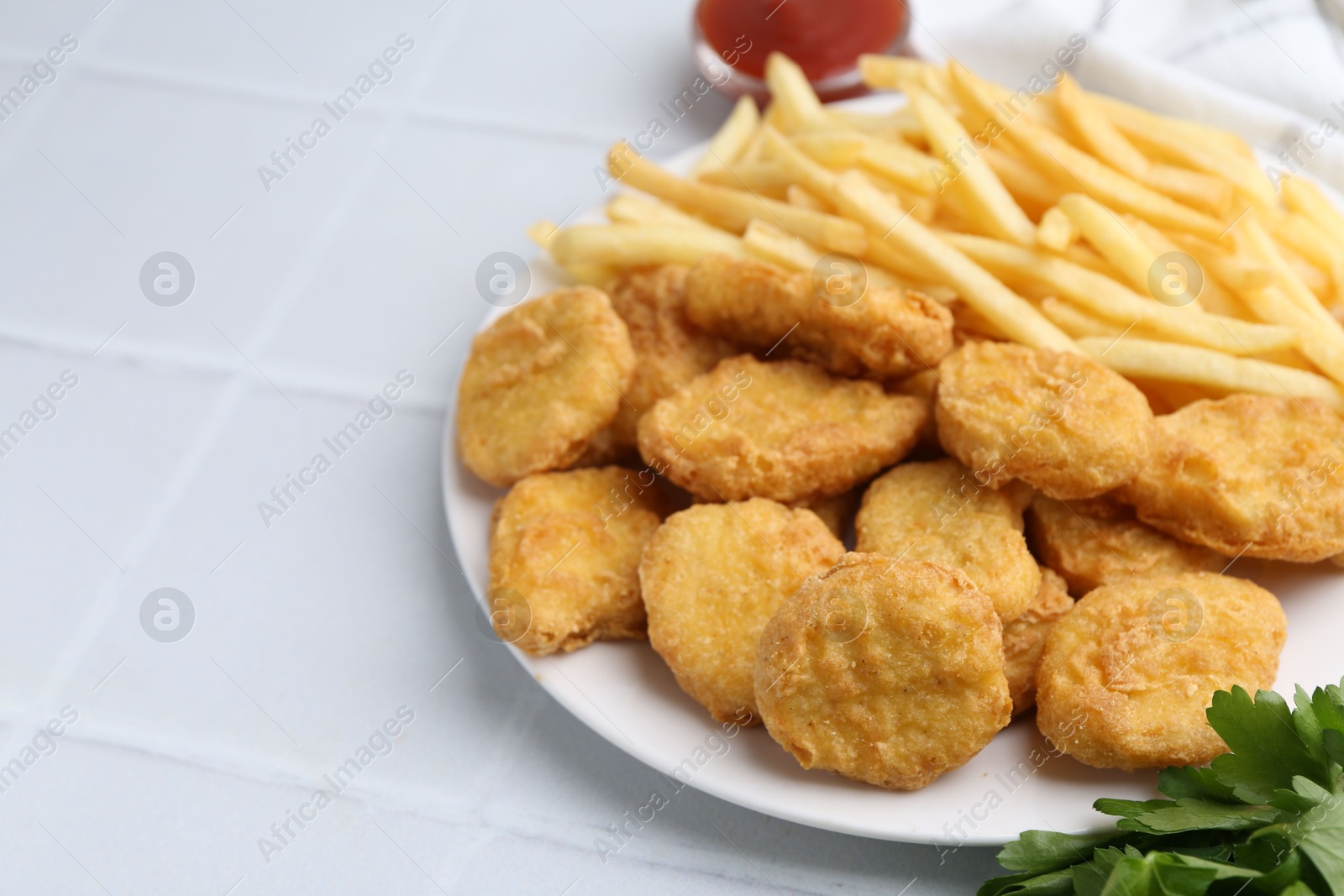 Tasty chicken nuggets and french fries on white tiled table. Space for text Photo of Tasty chicken nuggets and french fries on white tiled table. Space for text