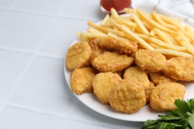 Photo of Tasty chicken nuggets and french fries on white tiled table. Space for text