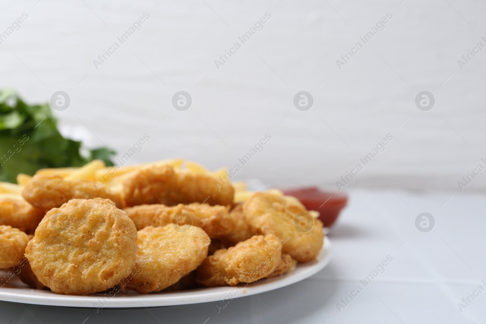 Tasty chicken nuggets and french fries on white tiled table. Space for text Photo of Tasty chicken nuggets and french fries on white tiled table. Space for text