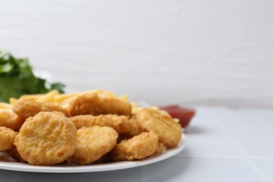Photo of Tasty chicken nuggets and french fries on white tiled table. Space for text