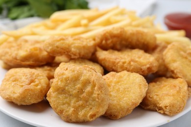 Photo of Tasty chicken nuggets and french fries on white table, closeup