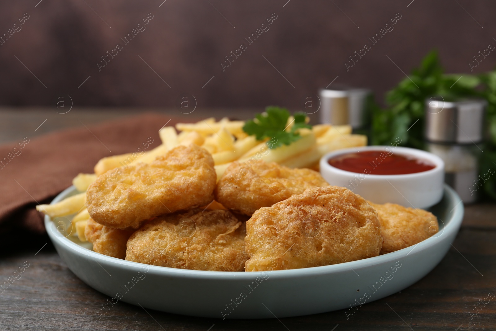 Tasty chicken nuggets and french fries with sauce on wooden table, closeup Photo of Tasty chicken nuggets and french fries with sauce on wooden table, closeup