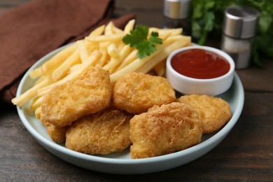 Photo of Tasty chicken nuggets and french fries with sauce on wooden table, closeup