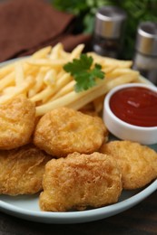 Photo of Tasty chicken nuggets and french fries with sauce on wooden table, closeup