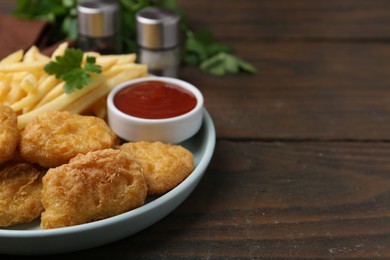 Photo of Tasty chicken nuggets and french fries with sauce on wooden table, closeup. Space for text