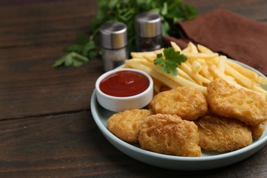 Photo of Tasty chicken nuggets and french fries with sauce on wooden table, closeup