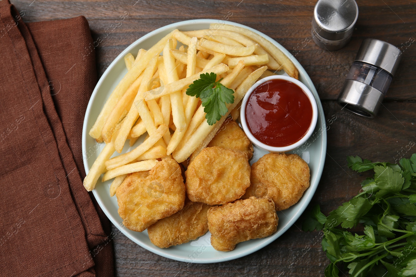Tasty chicken nuggets and french fries with sauce on wooden table, flat lay Photo of Tasty chicken nuggets and french fries with sauce on wooden table, flat lay