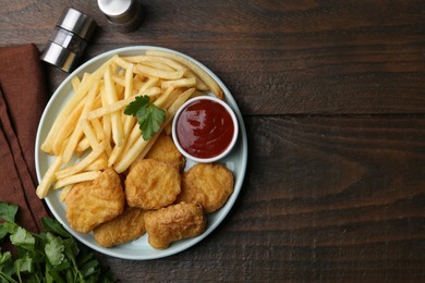 Photo of Tasty chicken nuggets and french fries with sauce on wooden table, flat lay. Space for text