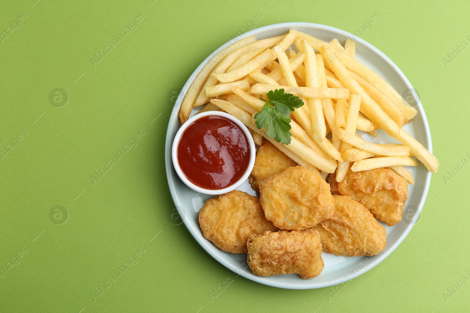 Tasty chicken nuggets and french fries with sauce on green background, top view. Space for text Photo of Tasty chicken nuggets and french fries with sauce on green background, top view. Space for text