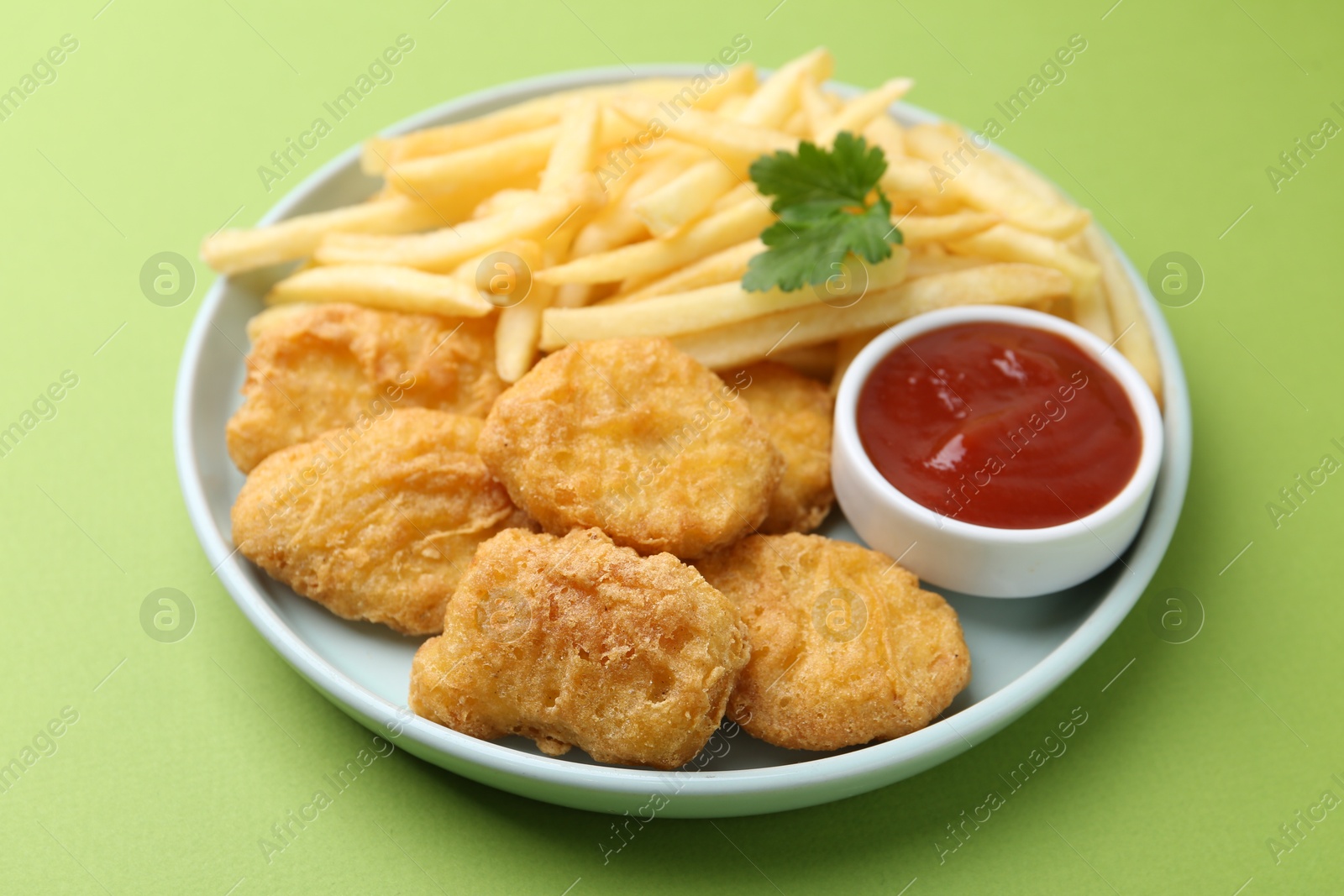 Tasty chicken nuggets and french fries with sauce on green background, closeup Photo of Tasty chicken nuggets and french fries with sauce on green background, closeup