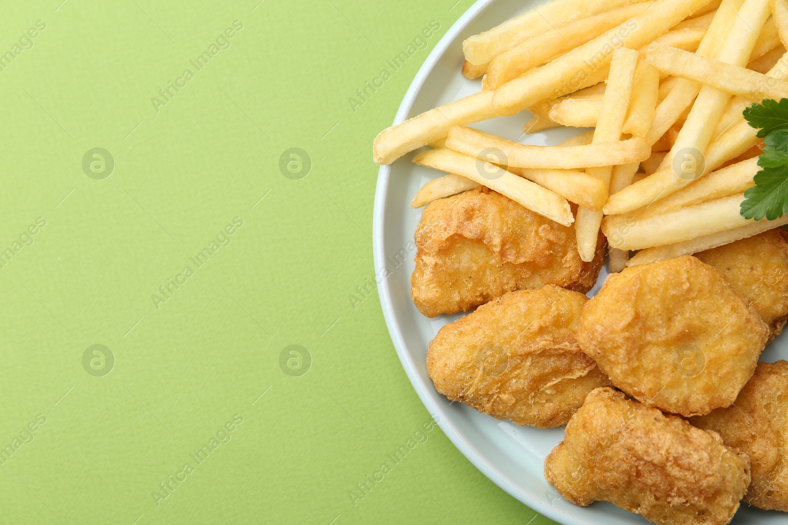 Tasty chicken nuggets and french fries on green background. Space for text Photo of Tasty chicken nuggets and french fries on green background. Space for text