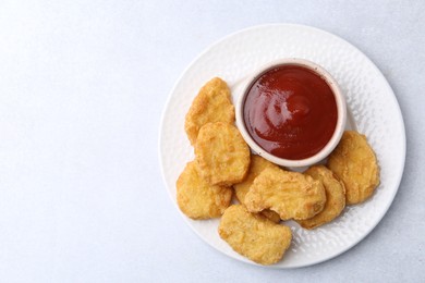 Photo of Tasty chicken nuggets with sauce on white background, top view. Space for text