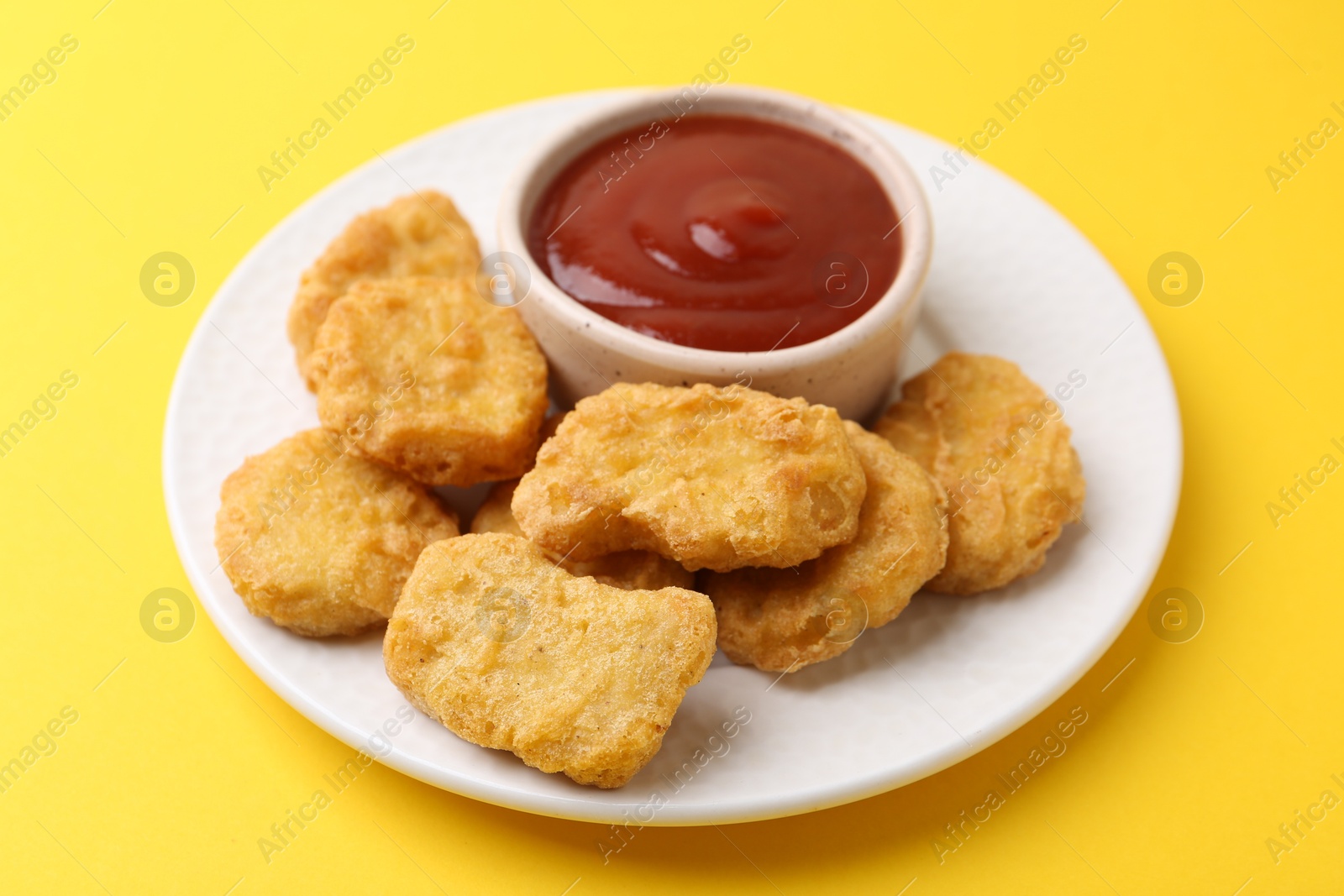 Tasty chicken nuggets with sauce on yellow background, closeup Photo of Tasty chicken nuggets with sauce on yellow background, closeup