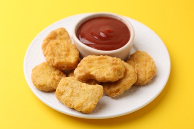 Photo of Tasty chicken nuggets with sauce on yellow background, closeup