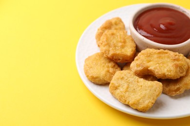 Photo of Tasty chicken nuggets with sauce on yellow background, closeup. Space for text
