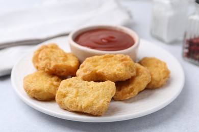 Photo of Tasty chicken nuggets with sauce on light table, closeup